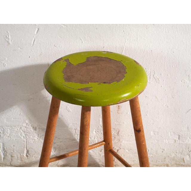 This antique wooden stool is a three-legged seat with a round seat and turned splayed legs joined by stretchers. It...