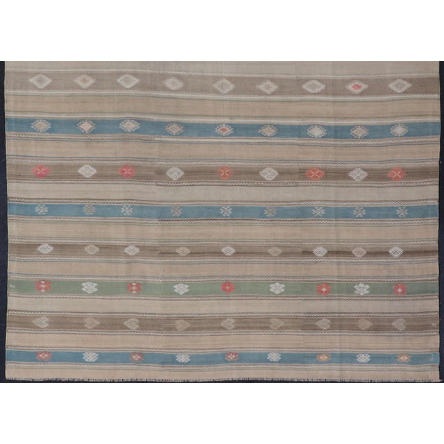 This flat-weave tribal kilim has been hand-woven in wool. The rug features a horizontal stripe design, accentuated by...