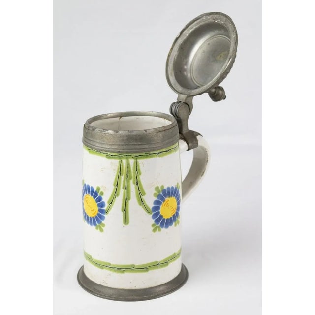 Glazed ceramic beer mug with polychrome floral decorations, pewter lid. The initials F.W. are engraved on the lid. 18th -...