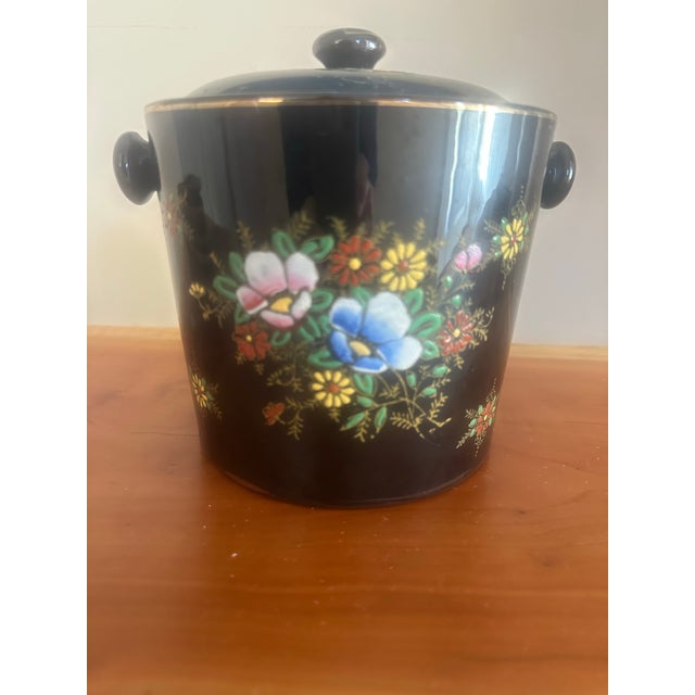 Charming vintage lidded pot featuring delicate hand-painted floral garlands in soft pastel tones. The rounded form, side...
