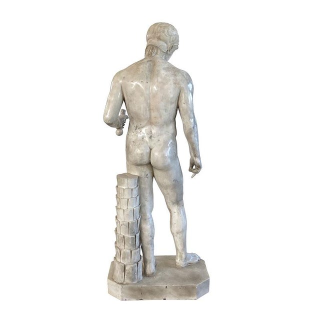 Entirely made of white marble. On a rectangular base with beveled edges, the statue represents the figure of a Greek hero...