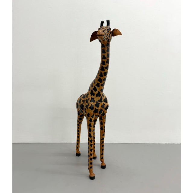 A whimsical hand-painted giraffe sculpture featuring an elongated silhouette and expressive hand-carved form. Crafted with...