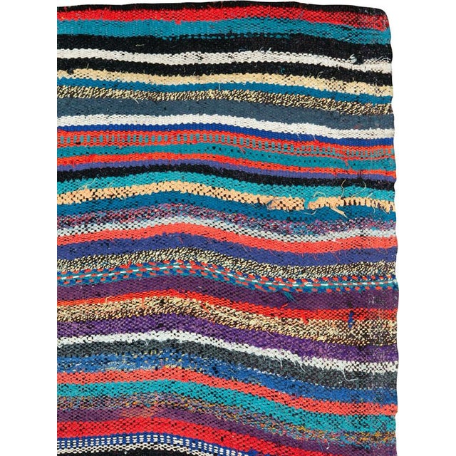 This mid-20th century Persian flatweave kilim rug is a lively expression of tribal artistry, defined by its flowing...