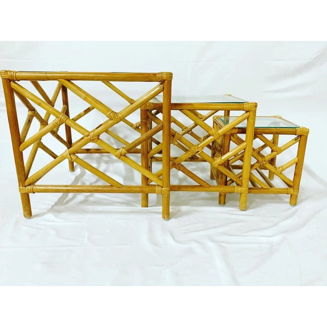 Bamboo rattan nesting tables with Chinese chippendale design and glass tops. These are three tables in total which nest...