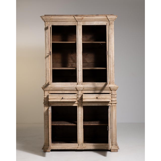A traditional oak vitrine featuring glazed upper doors for display and a solid lower section for storage. Late 19th...