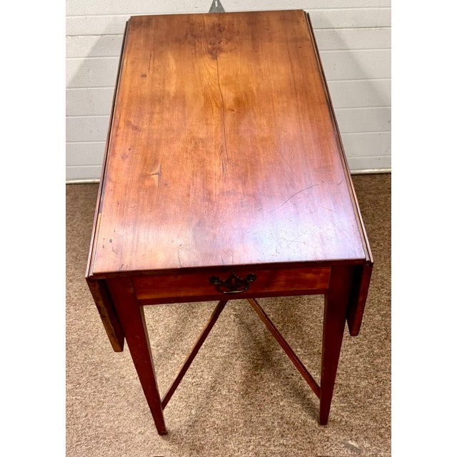 Hard to find antique American cherry dropleaf Pembroke table with a cross stretcher base and 1 drawer. Drawer is hand...