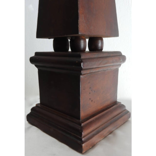 This is a vintage walnut obelisk dotted with worm holes. This tabletop piece features a square base and has four non-...