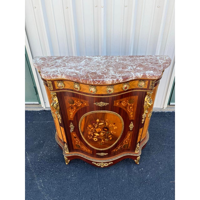 Italian console cabinet in the Louis XV style. Patterning utilizing satinwood, walnut, and other exotic woods create...