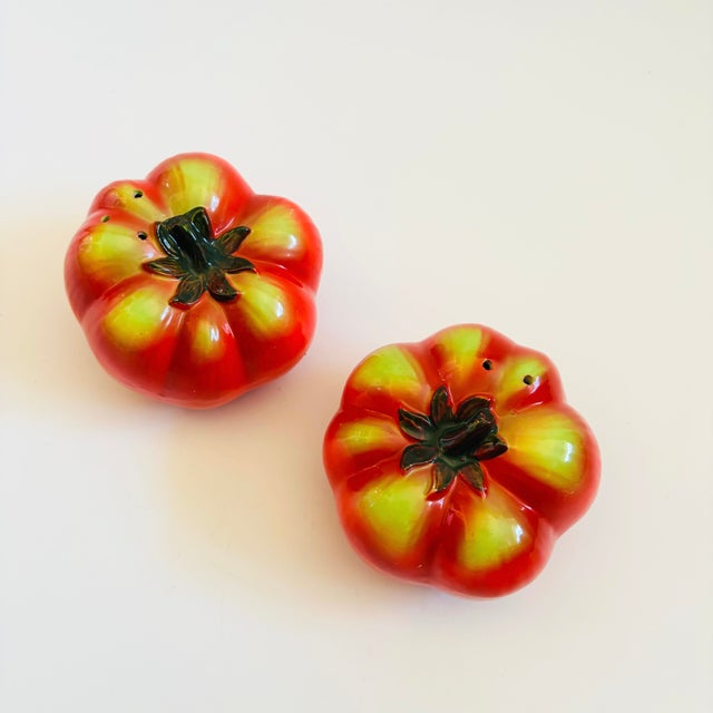 A pair of vintage ceramic salt and pepper shakers in the shape of tomatoes, each with a removable stopper - one is cork...