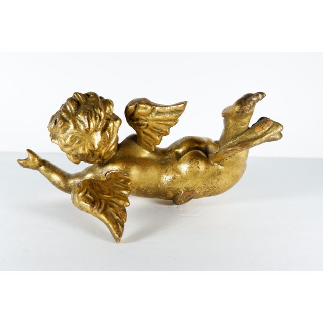 An antique wood carved gold gilt flying winged Putti. Putti is in the flying position. Measures 10” long, 3 ½” high and 6...