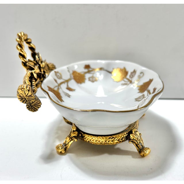 A gorgeous gilt gold-detailed and porcelain soap dish. It sits in a gilt metal floral and tassel footed base. Dimensions...