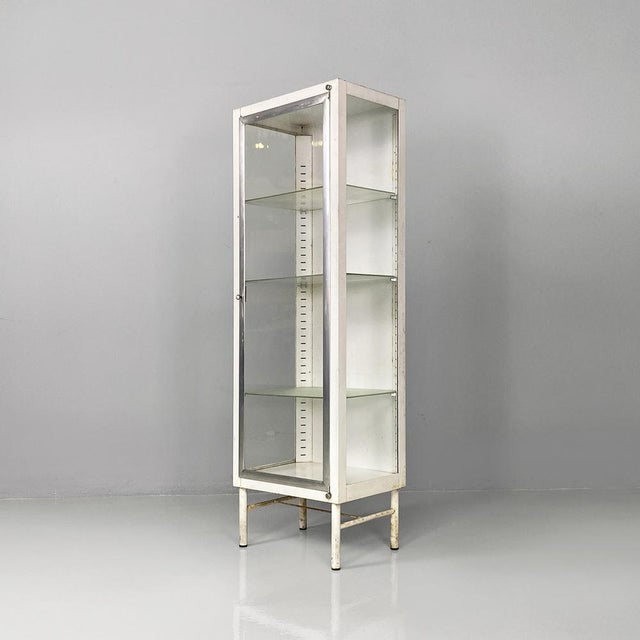 Italian mid-century white metal and glass old pharmacy display cabinet, 1950s. Square-shaped metal display cabinet, with...