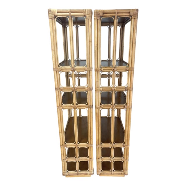 A striking pair of vintage rattan étagères featuring chunky pole construction and architectural fretwork sides. The open...