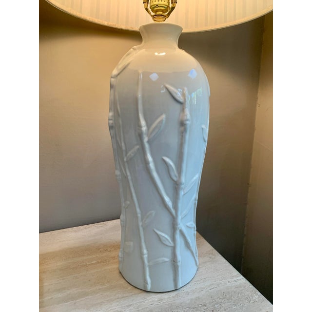 Elegant Hollywood Regency, white, ceramic, faux bamboo, embossed table lamp with a pleaded, white shade. The bamboo stalks...