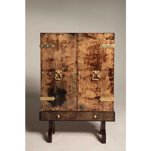 Aldo tura dry bar. Brown parchment, brass hardware, two drawers, two doors lit from within from 1950s period. Internally...