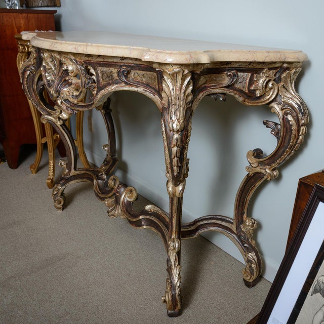 Regency style marble top console table with a cream and tan veined top and shaped edge. The finish is a subdued silver,...