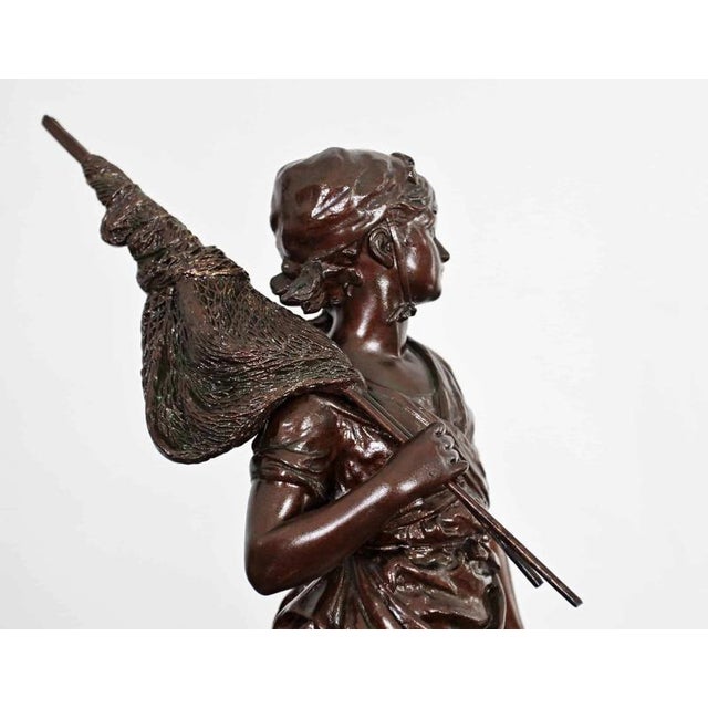 Detailed statue of a young woman carrying a net and a basket of fish made of zinc-tin alloy with a beautiful patina on a...