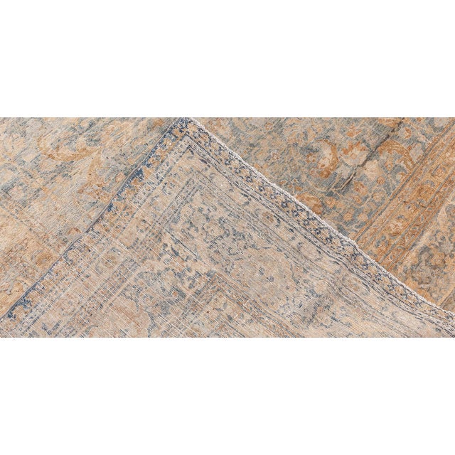 This turn of the century antique Persian Tabriz carpet features an all over grey-blue background garden design in a muted...