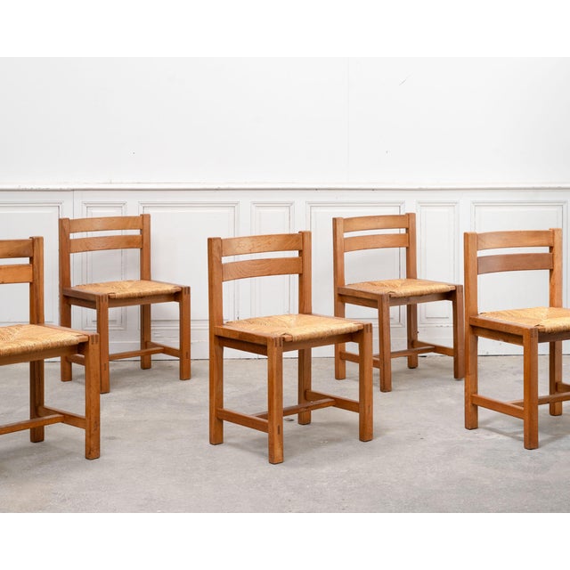 A beautiful set of six vintage chairs from Regain, crafted from solid elm with woven straw seats. Their understated and...