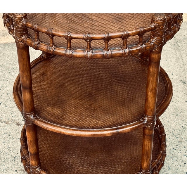 A vintage round three-tier end table in bamboo, with woven rattan table tops, in the style of McGuire. Use this table as a...