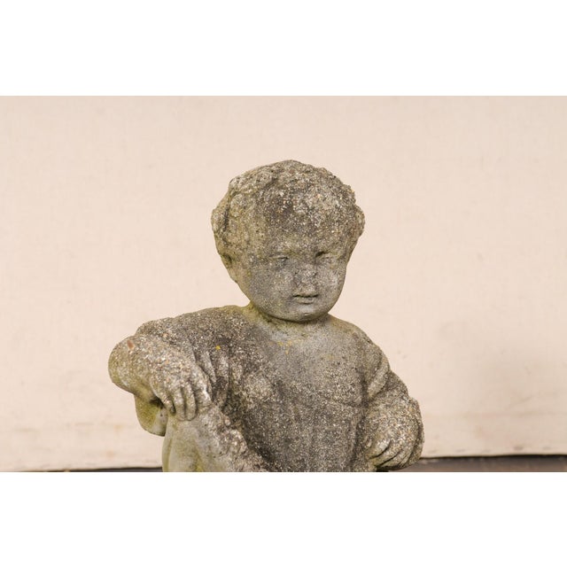 A French cast-stone cherub or bambine garden statue from the mid 20th century. This vintage garden element from France has...