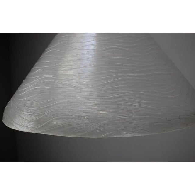 Elegant vintage pendant lamp dating from the 1970s, featuring a sculptural white glass shade with an unusual flowing...