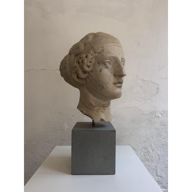 Carrara marble sculpture depicting the head of a young woman from the second half of the 19th century. This Hellenistic-...