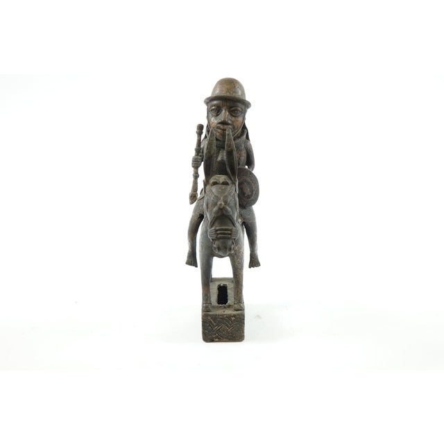 This Antique Bronze African Sculpture of an African Warrior measures 8” x 4.5” x 12.5” and depicts a warrior riding a...