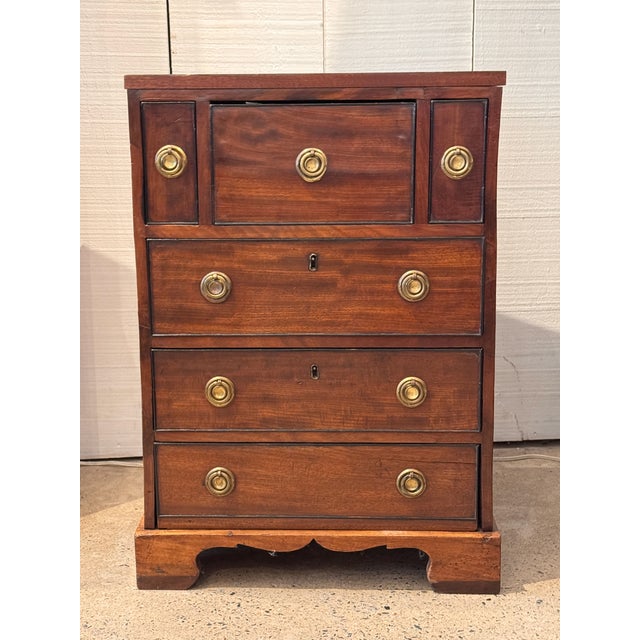A small mahogany chest with an unusual drawer arrangement — two narrow drawers flank a wider center drawer at the top,...