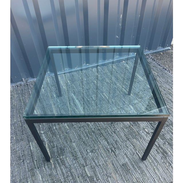 Square coffee table with a matte black lacquered metal frame and a 1.5 cm thick glass top. Please note, as shown in the...