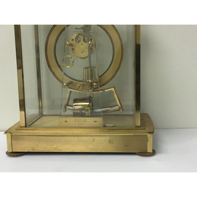 A mid-century brass and glass mantle clock made by West German clockmaker Kieninger & Obergfell with a brass frame and...