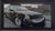 Realism Camp Washington Caddy by Brad Davis | Oil on wood panel Black car with damage parked on street For Sale - Image 3 of 5