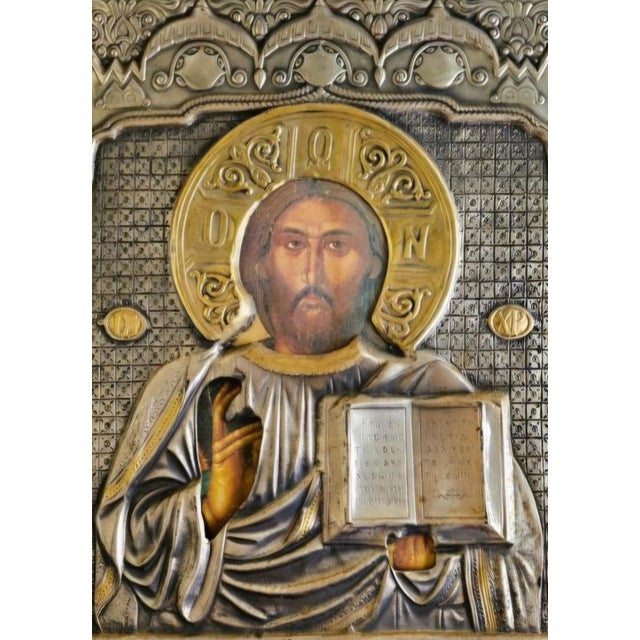 An elegant 19th-century Orthodox icon crafted in silver, mounted on a wooden support. The silver surface is finely worked...