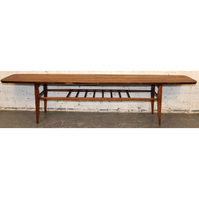 A classic mid-century surfboard-form coffee table crafted in warm walnut, featuring elegantly tapered ends and a long,...