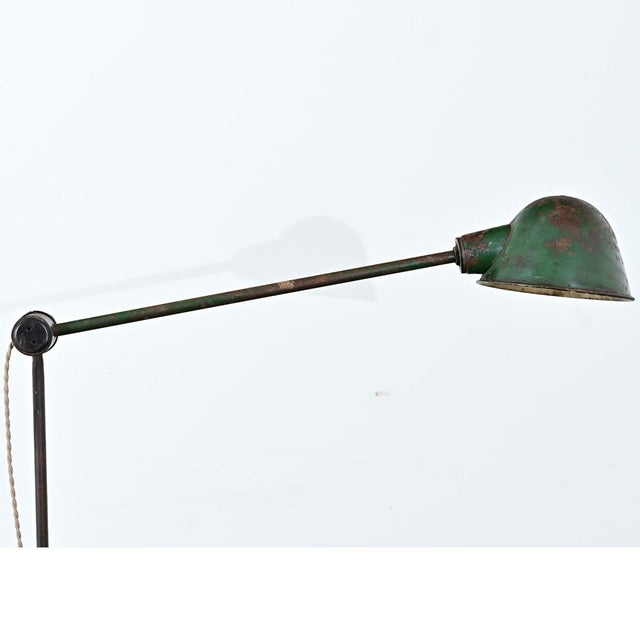 A French industrial floor lamp with a cast iron base and adjustable steel arms. From top to bottom, the surface of the...