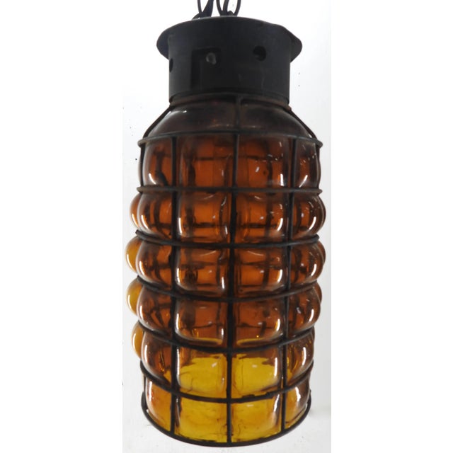 Amber glass has been blown between the ribs of this pendant light fixture for a unique style. The metal is finished in...