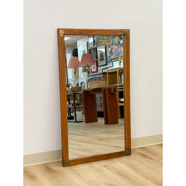 This vintage mirror from Dixie's Act II collection showcases a warm walnut-toned wood frame accented with brass detailing,...