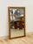 This vintage mirror from Dixie's Act II collection showcases a warm walnut-toned wood frame accented with brass detailing,...
