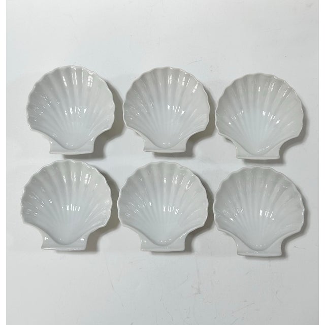 Set of six vintage white porcelain dishes shaped like scallop shells, with softly fluted detailing and a glossy finish....