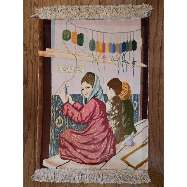 Hand-knotted Persian pictorial rug depicting a weaving workshop scene with women and dyed skeins of yarn. This is a...