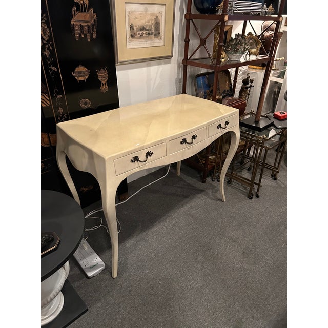 Elegant cream colored lacquered parchment writing desk that looks like goat skin, with bronze handles and cabriole legs....
