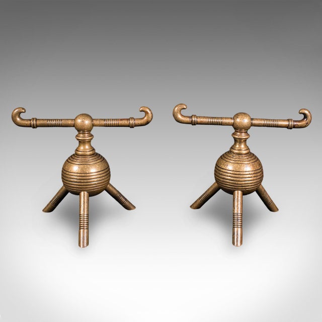 This is a pair of antique fireside tool rests. An English, brass fire dog in Aesthetic Movement taste by Dr Christopher...