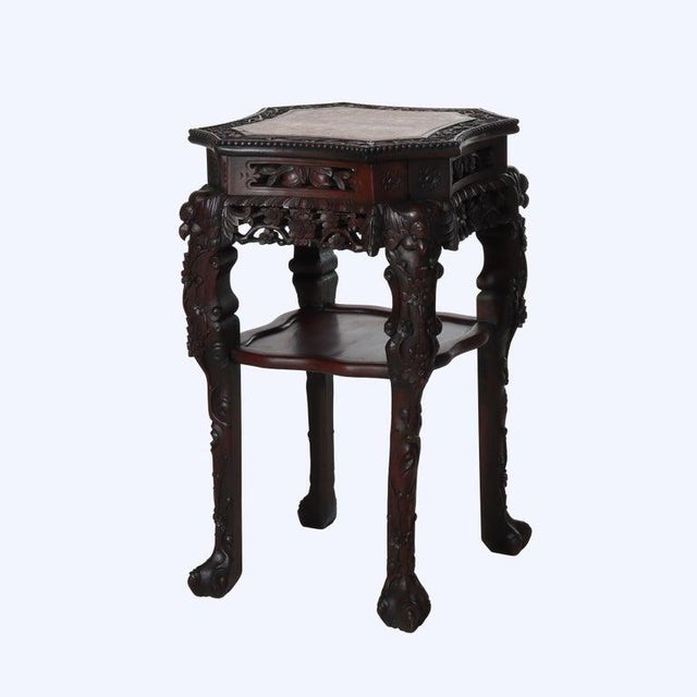 A Chinese antique side table, crafted from richly toned rosewood around 1920. The piece features an octagonal top inlaid...