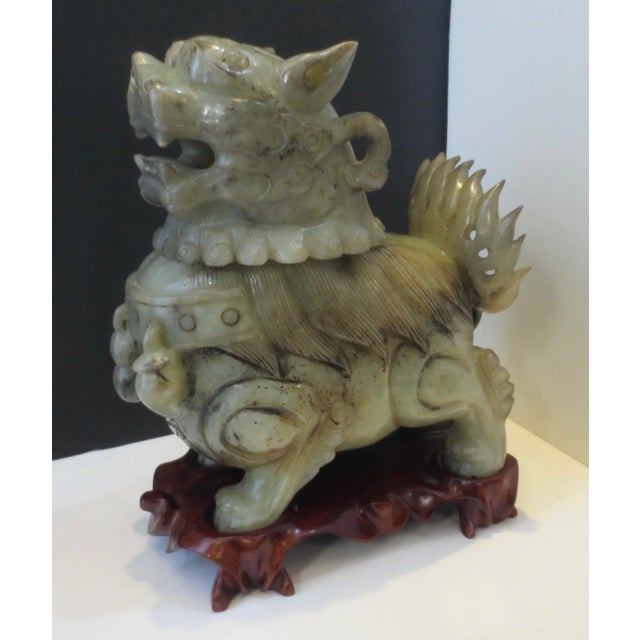 Chinese Hetian Jade carved Foo Dog sensor on a wooden base. Carved base to fit the four-footed stand of the dog. Olive to...