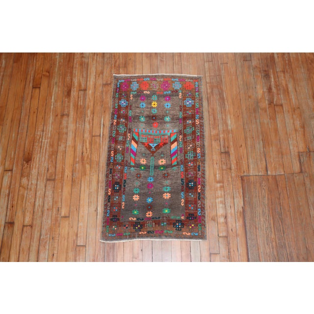 A vintage Anatolian Turkish rug mat with a brown field, cotton accents in electric blue, pink, teal, green, turquoise and...