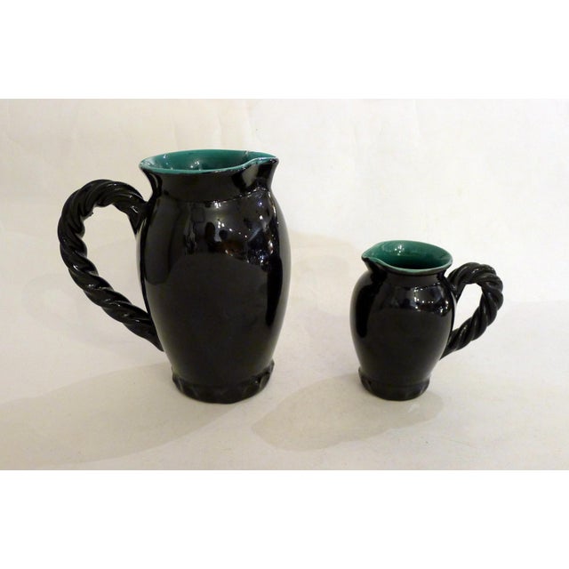 Pair of mid-century pitchers, with attractive twisted/braided handles in relief, one large (H 17 cm x 15 cm x 10 cm) and...