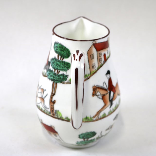 A vintage fine bone china creamer pitcher in Crown Staffordshire’s classic “Hunting Scene” pattern, showcasing English...