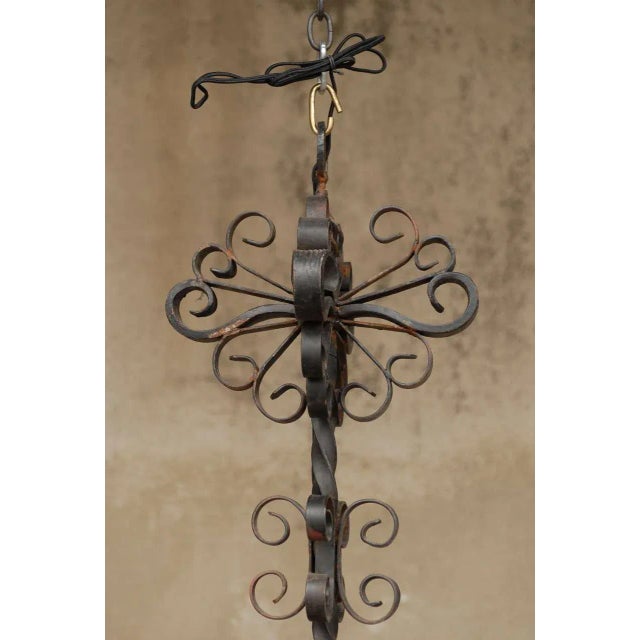 A French forged iron four-light chandelier. This French vintage forged iron chandelier features a compound of curls in its...