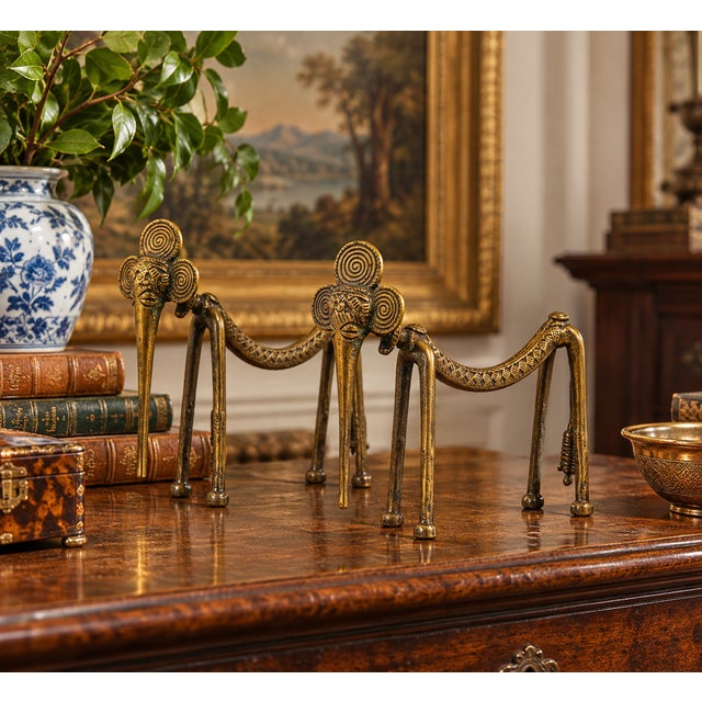 A distinctive pair of vintage West African style lost-wax brass elephant sculptures, each rendered with an elongated...