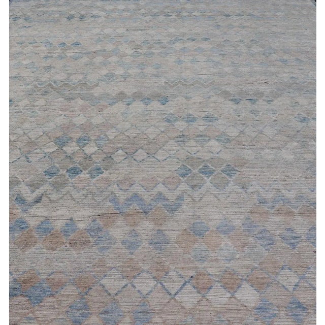 This over sized modern casual palace sized rug features a subtle diamond design rendered in blue, taupe, cream. This piece...